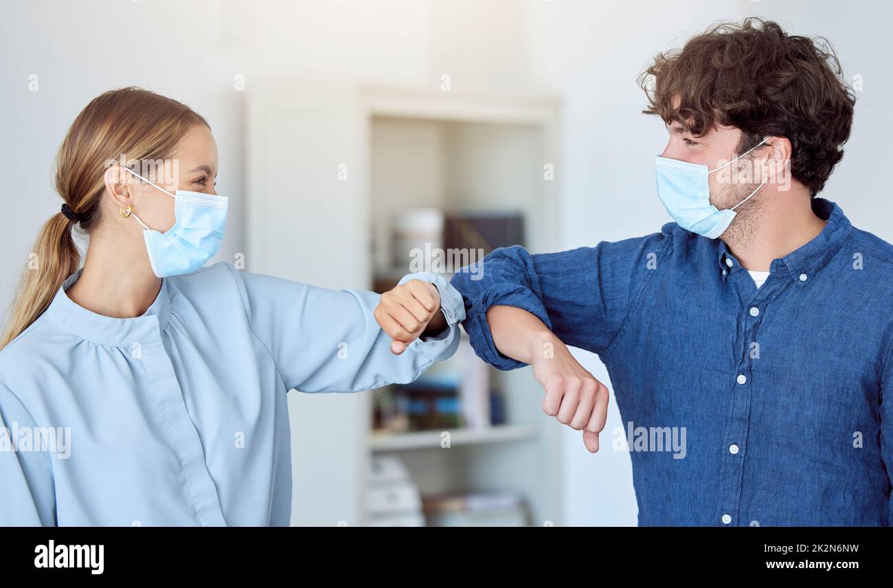 Business team, elbow bump and covid compliance with employees greeting with social distance in an office. Man and woman in the office during Stock Photo