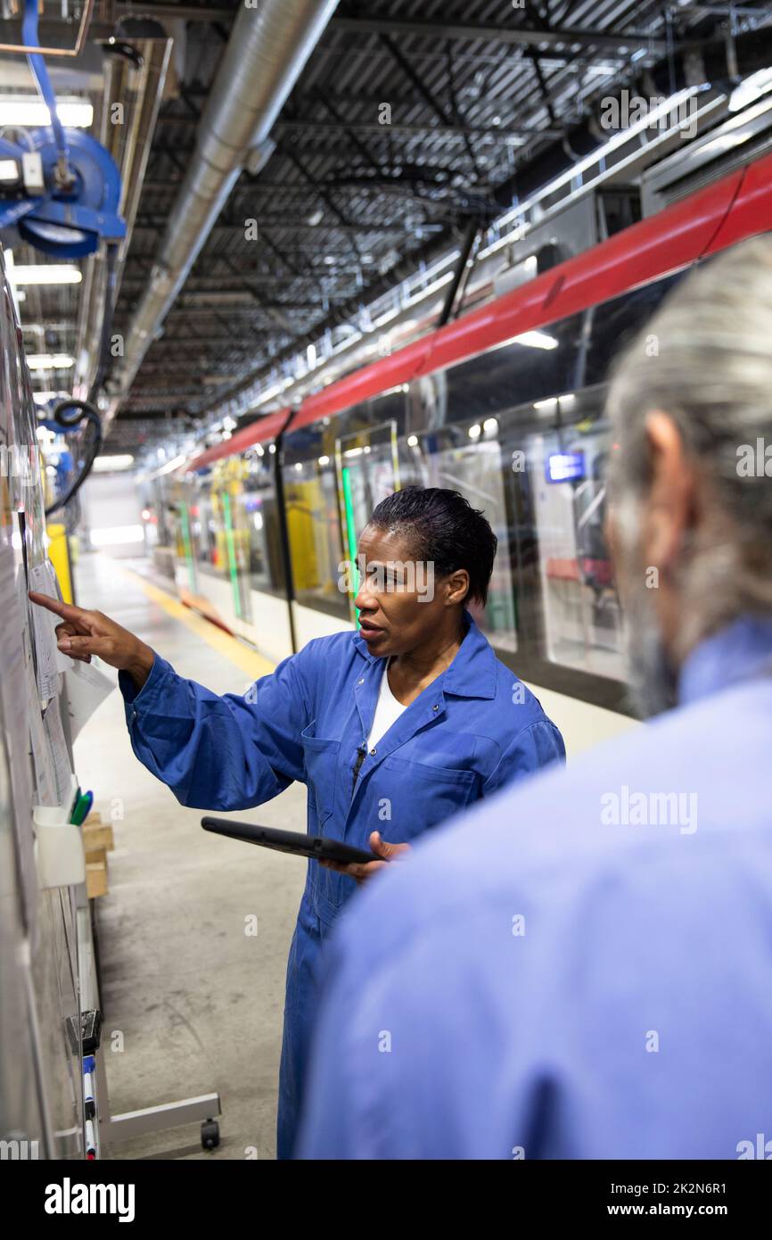 Transit workers talking at board in maintenance facility Stock Photo