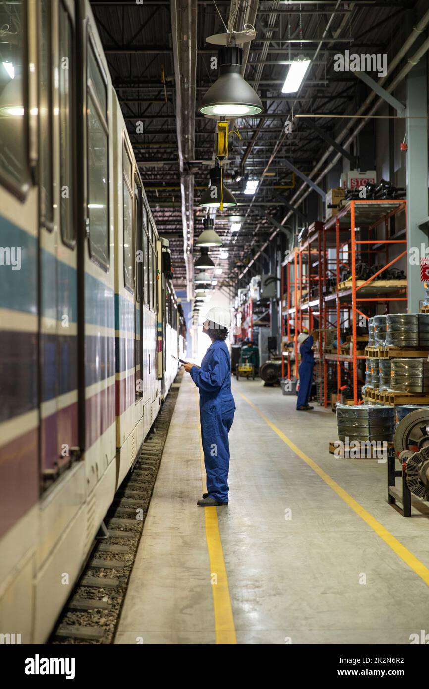 Female transit engineer inspecting subway in maintenance facility Stock