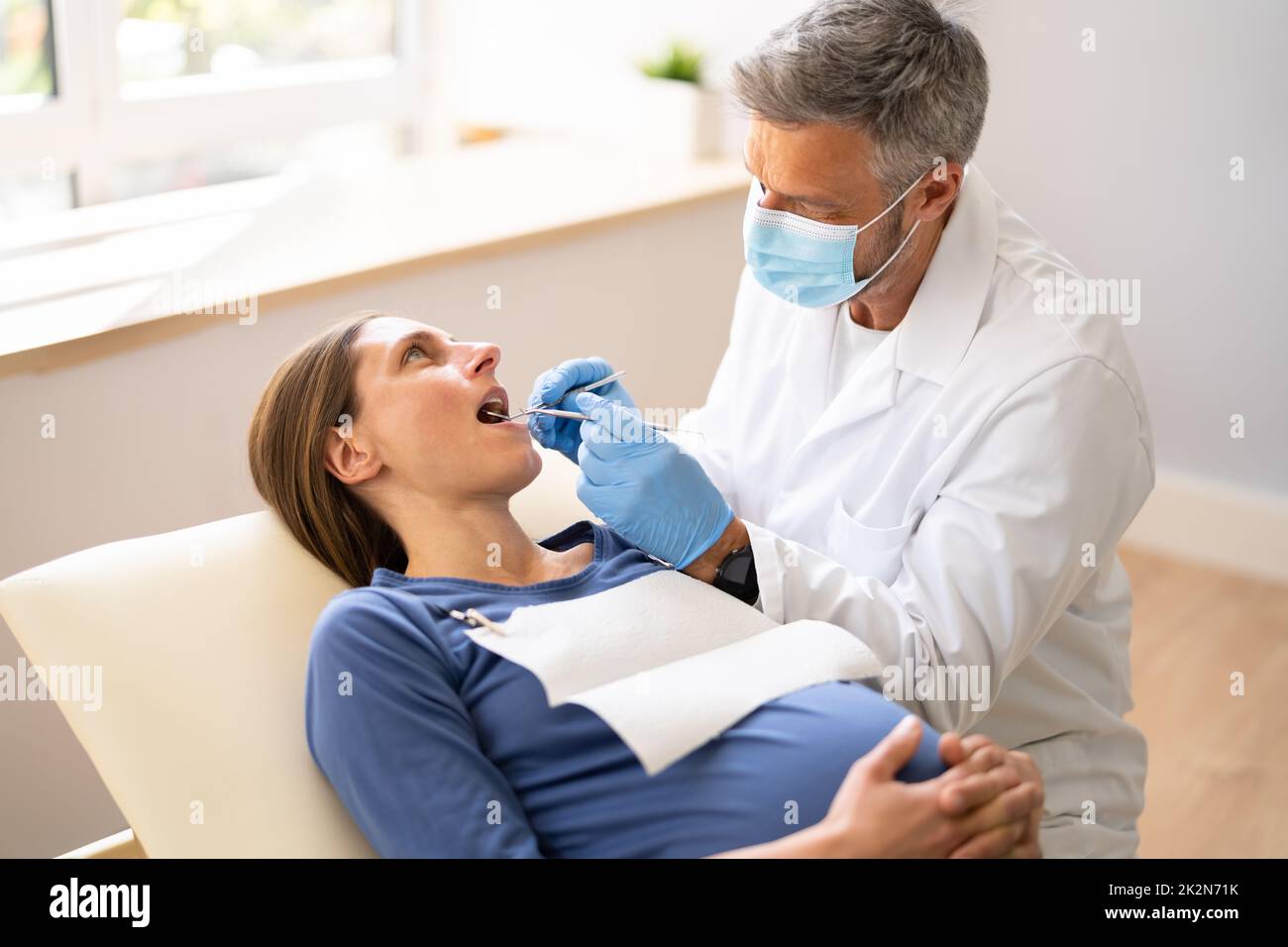 Male Dentist Treating Teeth Of Young Pregnant Woman Stock Photo Alamy