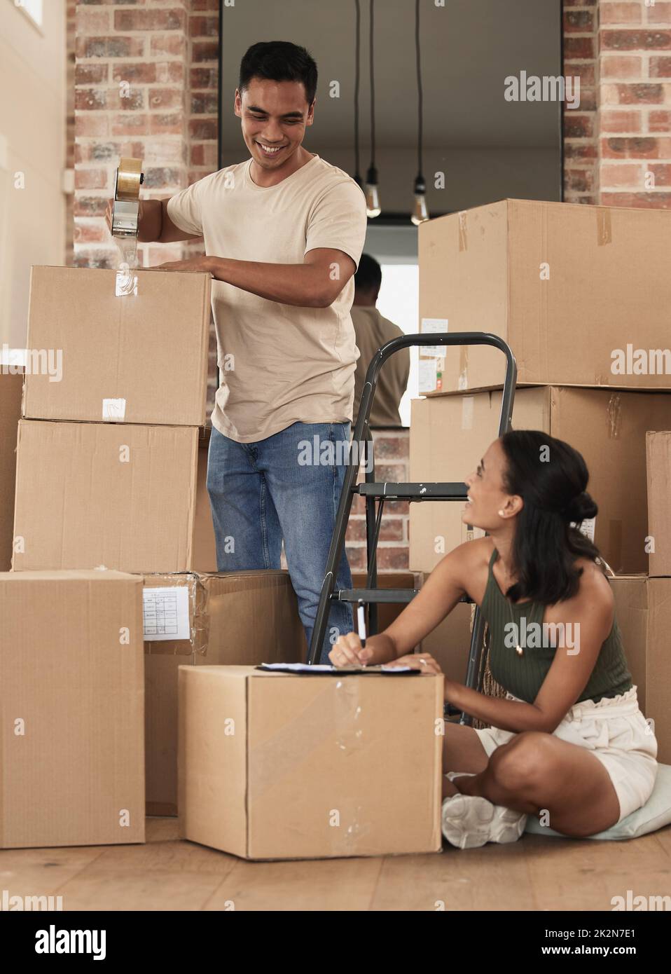 We are most alive when were in love. Shot of a young couple packing up to move in a room at home. Stock Photo