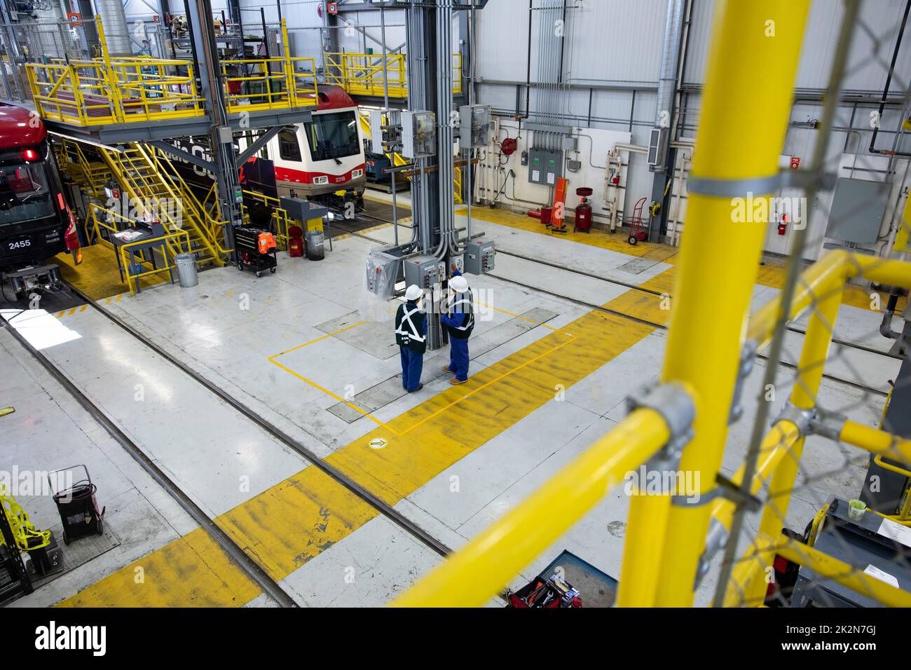 Transit workers operating equipment in maintenance facility Stock Photo