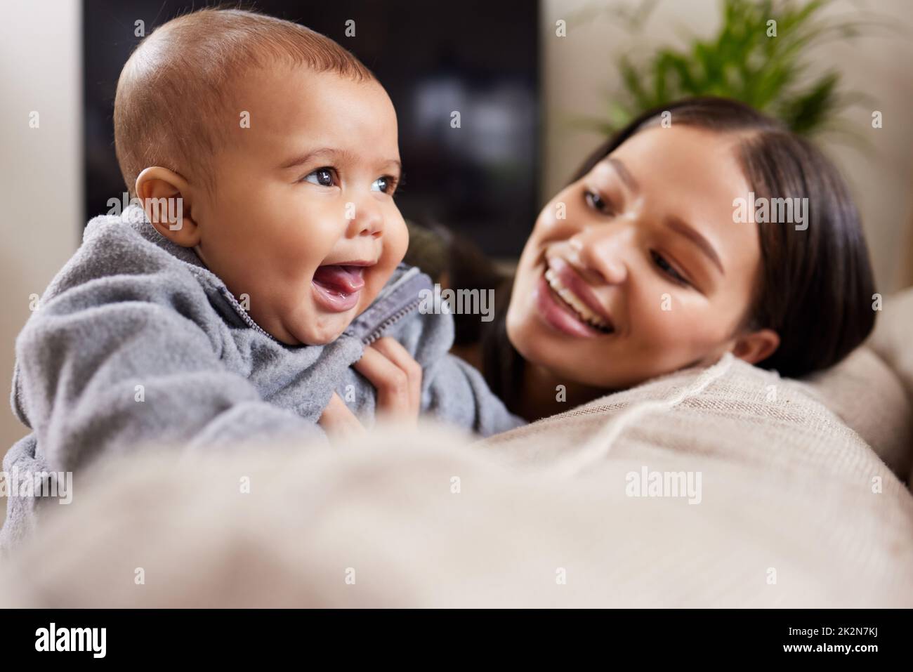 A babys smile can give you power. Shot of a young woman relaxing with her adorable baby on the sofa at home. Stock Photo
