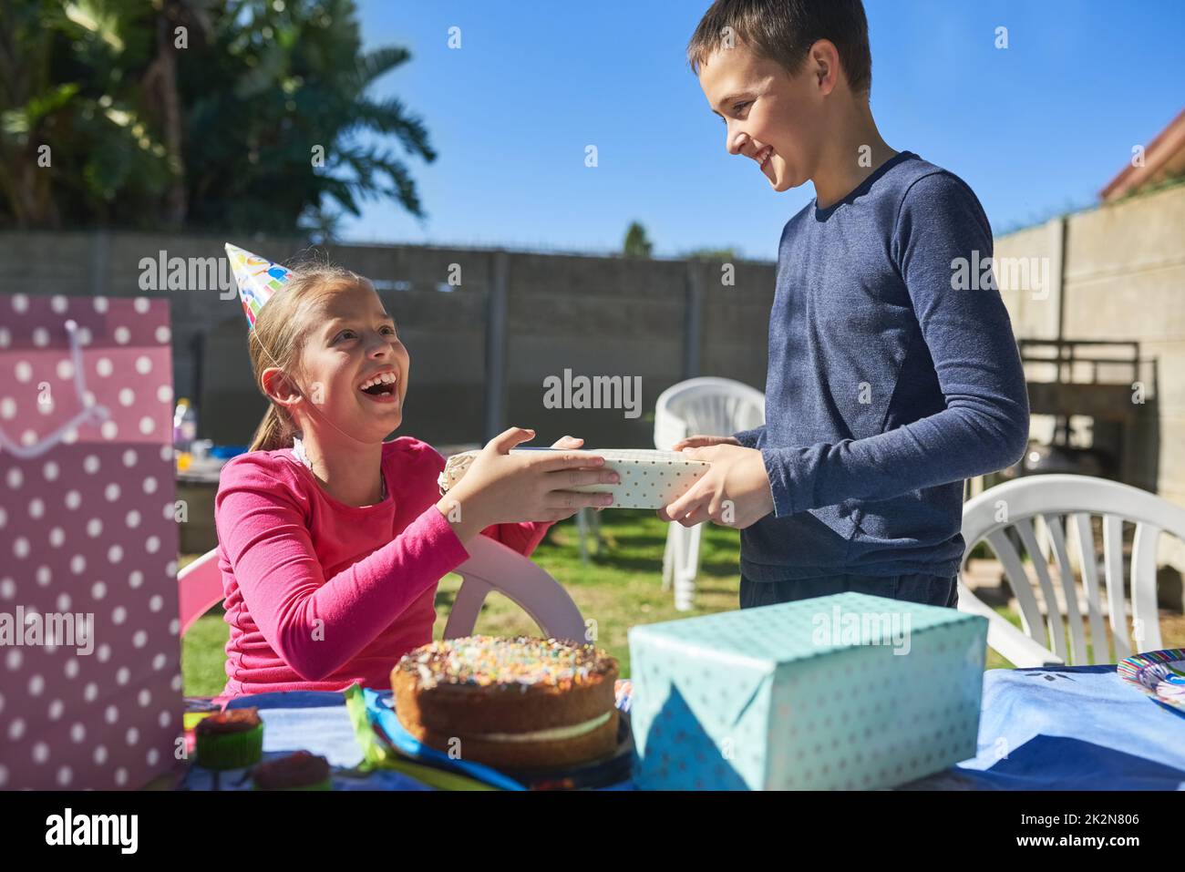 Showering the birthday girl with prezzies. Shot of the birthday girl receiving a present from a party guest. Stock Photo