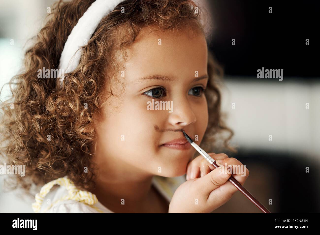 I wont wash this off. Shot of a little girl painting her face to look