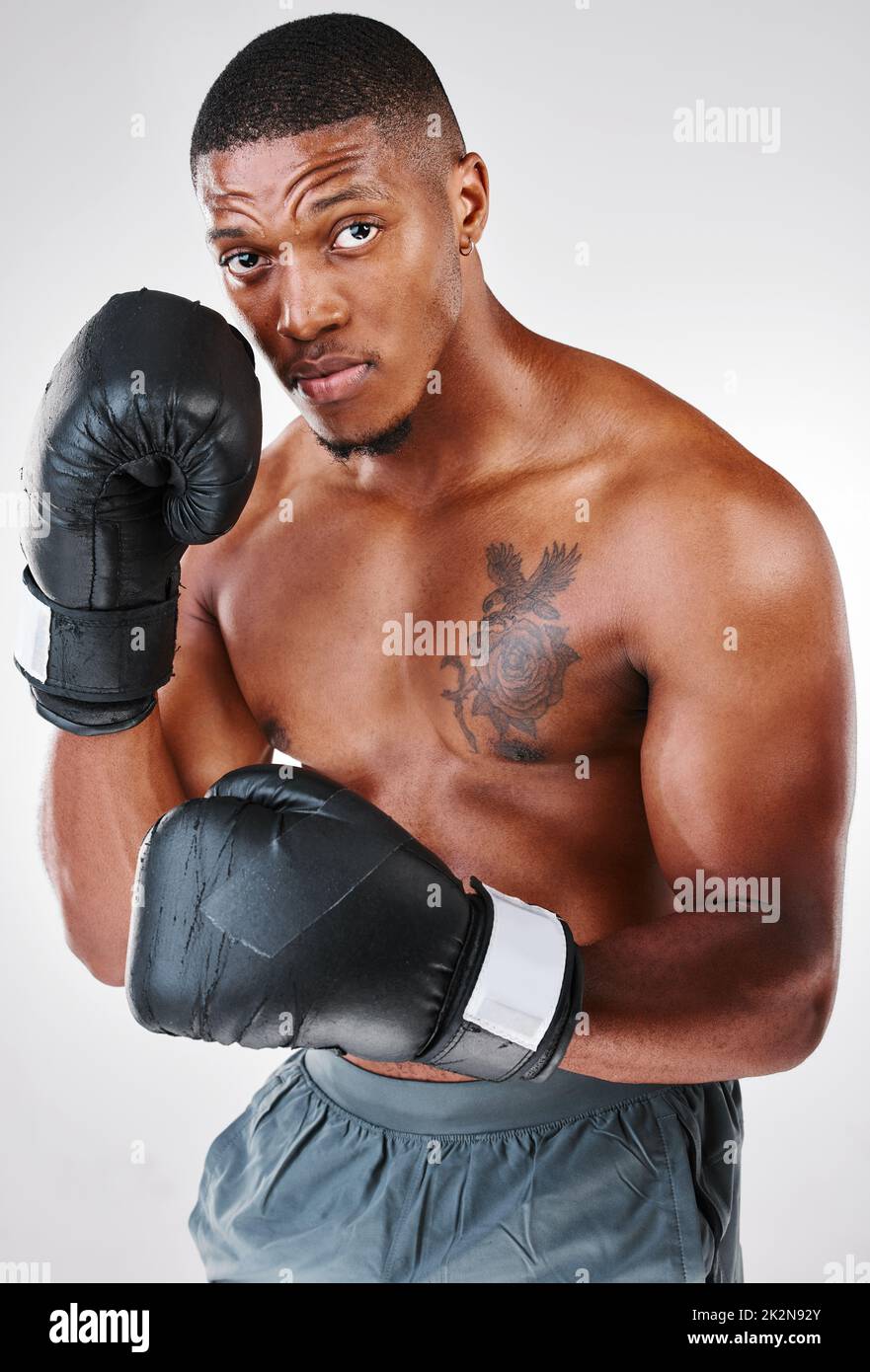 Ill enjoy it when you stumble. Studio portrait of a young shirtless man posing with boxing gloves against a white background. Stock Photo