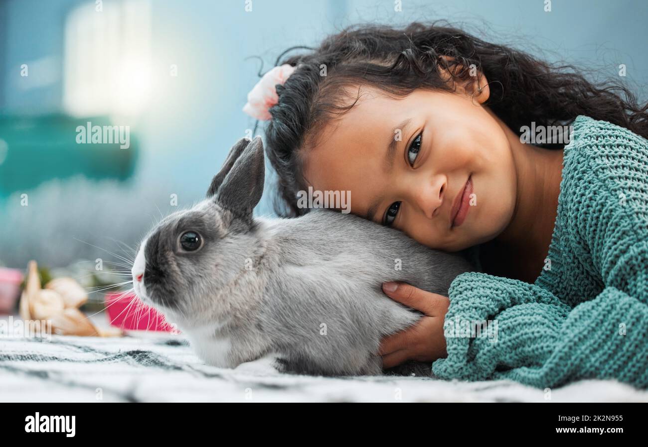Hes my best friend. Shot of an adorable little girl bonding with her pet rabbit at home. Stock Photo