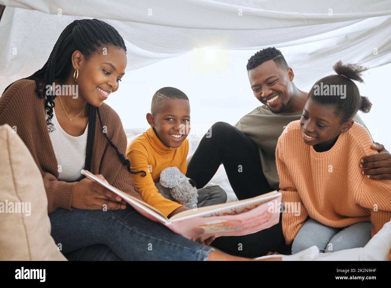 Is this still your favourite story. Shot of a young family reading a story together. Stock Photo