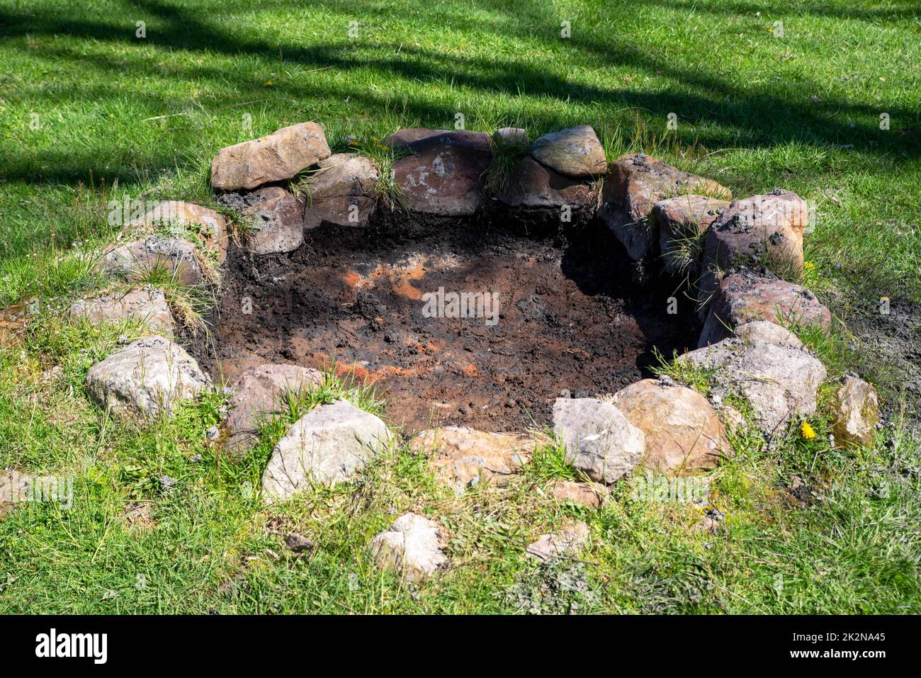 rustic stone circle fire pit in sunny grass background Stock Photo