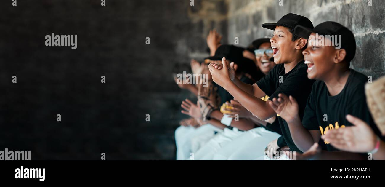 Cheering on their team. Cropped shot of a group of young baseball players cheering and supporting their team from the bench during a game. Stock Photo