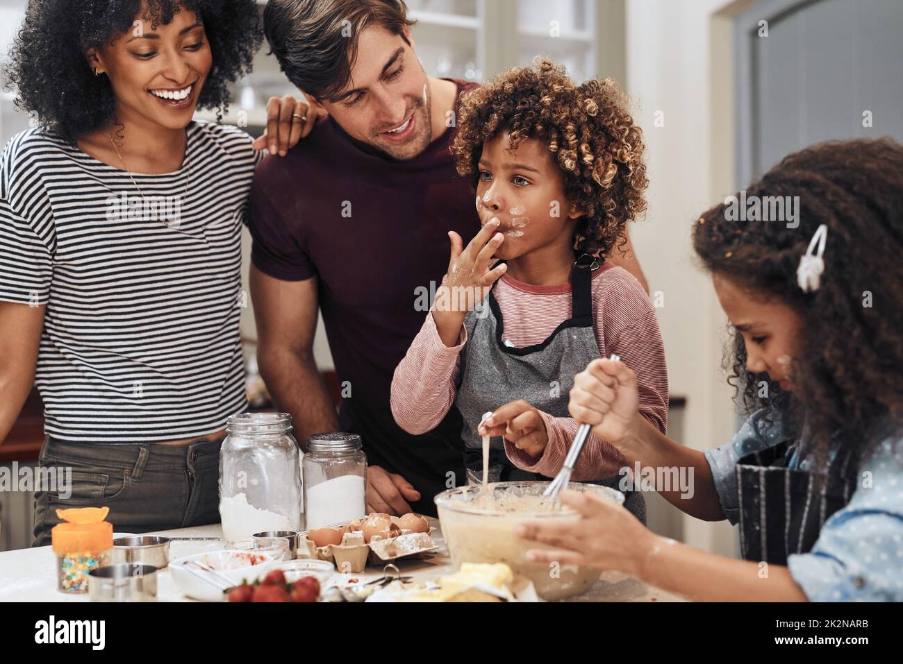 I can tell its going to be delicious. Cropped shot of a young couple baking at home with their two children. Stock Photo