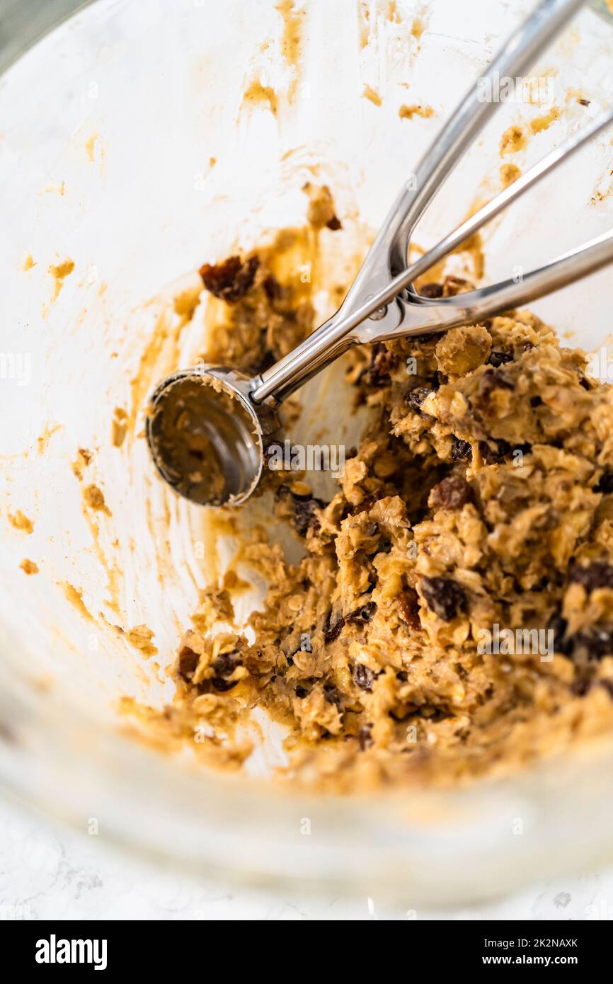 Scooping cookie dough with dough scoop into a baking sheet lined with  parchment paper to bake soft oatmeal raisin walnut cookies Stock Photo -  Alamy
