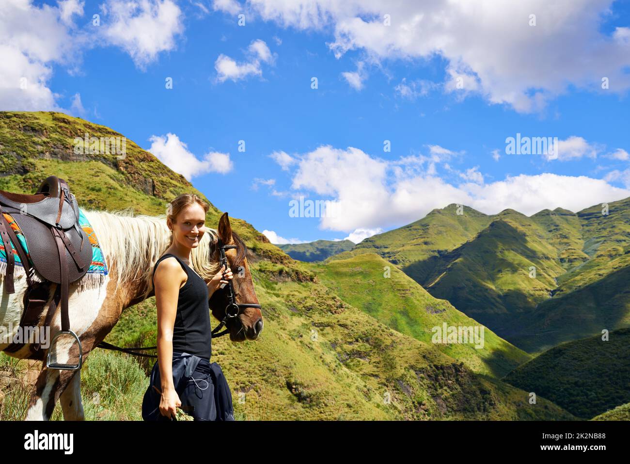 On top of the world. A young woman with her horse on a mountain trek. Stock Photo