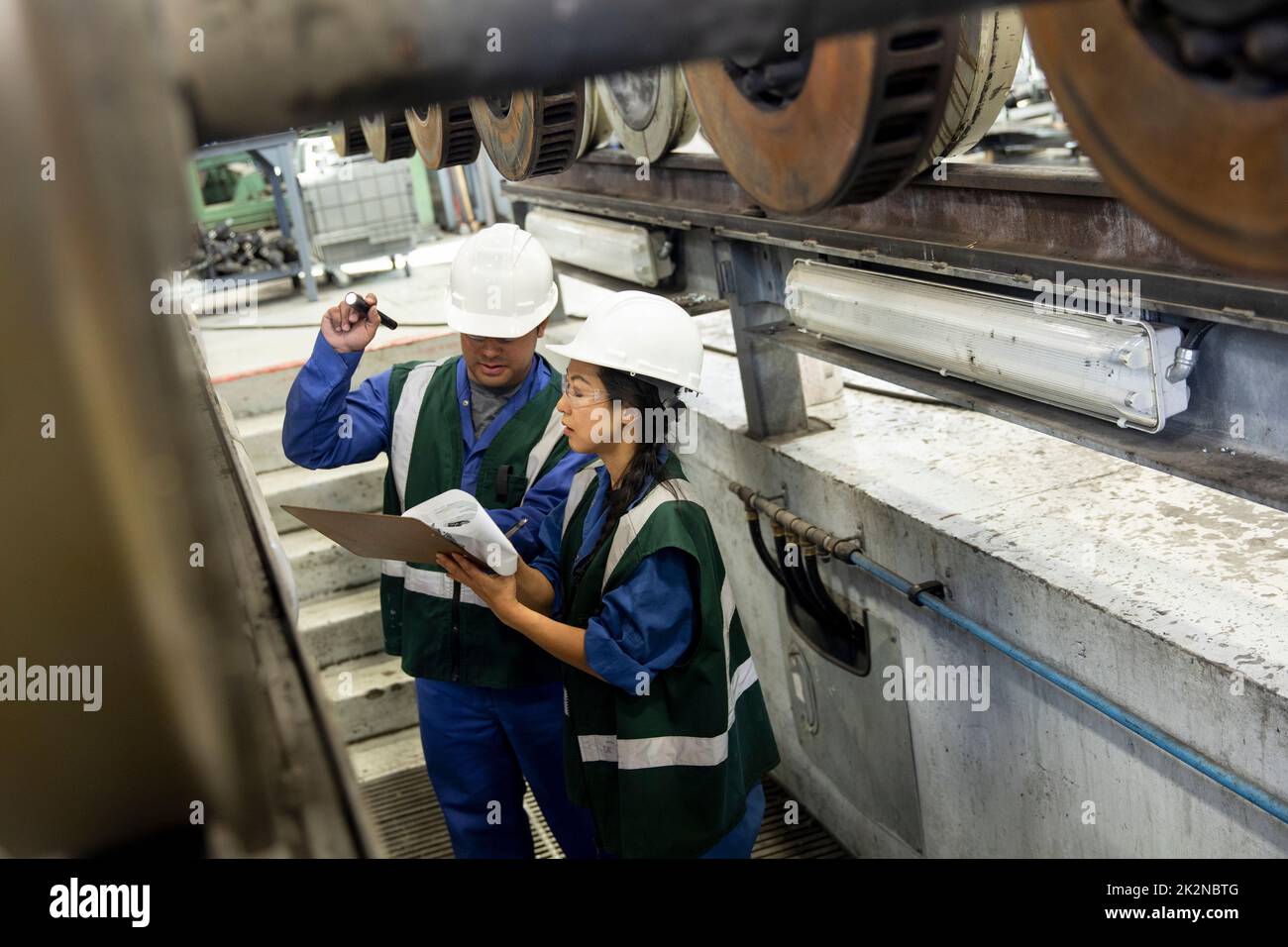 Transit engineers inspecting axles in maintenance facility Stock Photo