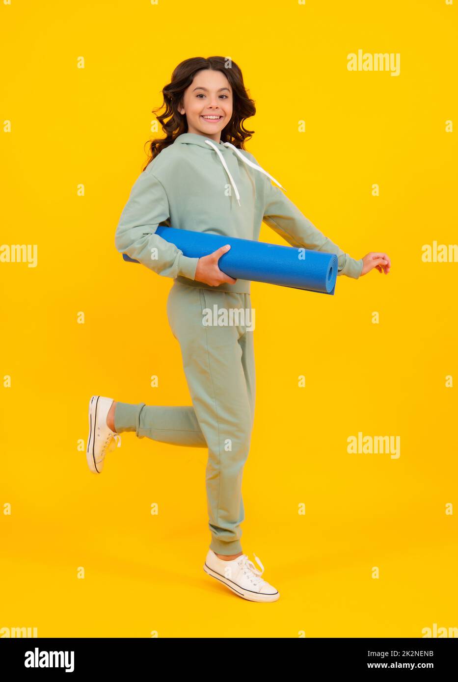 Teenage girl in track suit, fashion sports wear isolated on yellow background. Fitness sport child in sportswear sports clothing and shoes. Stock Photo