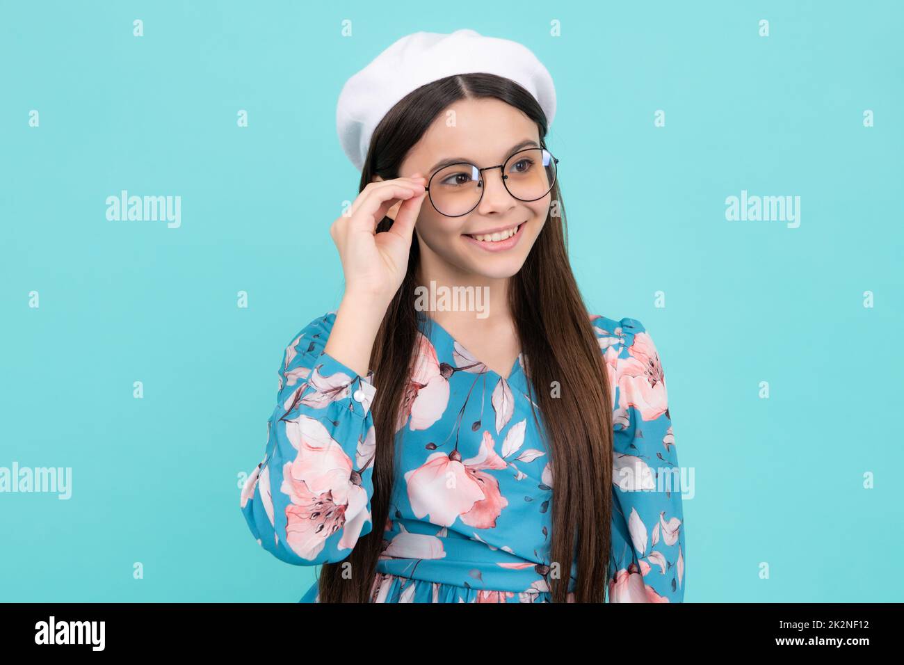 Headshot portrait of cute teenager child girl isolated on blue studio background wear glasses look at camera, kid eyesight treatment concept. Happy Stock Photo