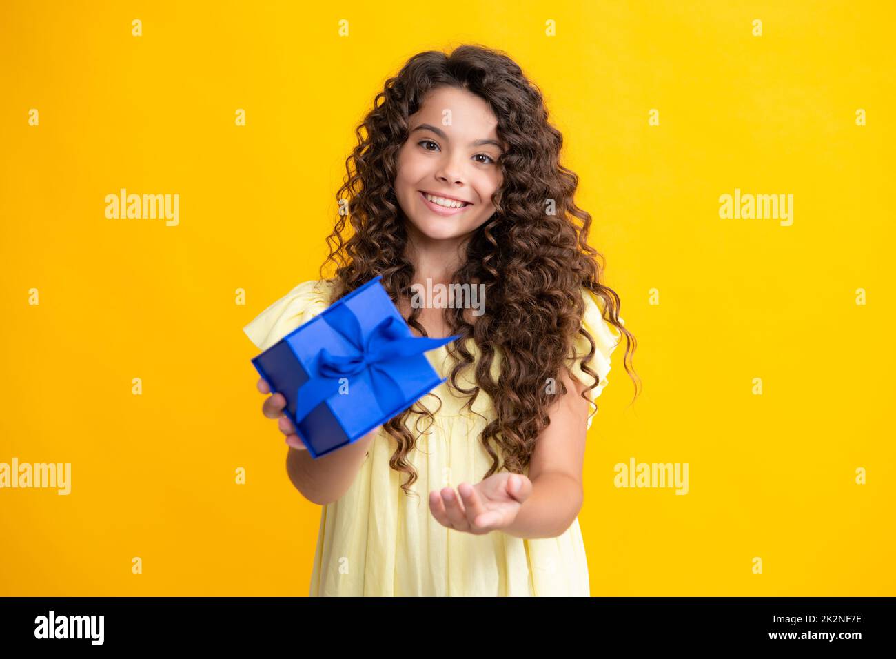 Happy teenager portrait. Child with gift present box on isolated background. Presents for birthday, Valentines day, New Year or Christmas. Smiling Stock Photo