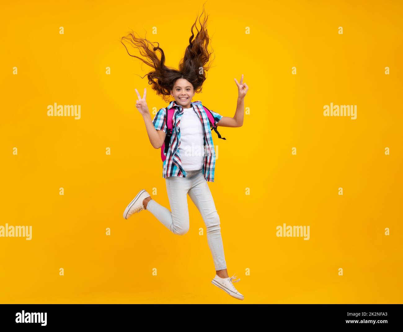 School teen girl in with backpack. Teenager student on isolated background. Run and jump. Kids learning, education, studying and knowledge. Stock Photo