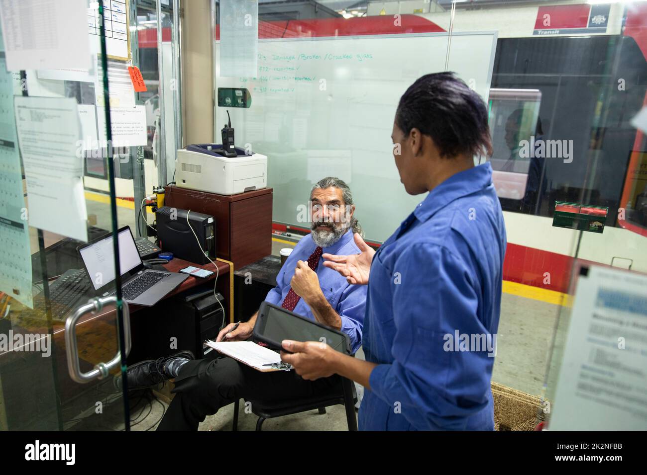 Transit worker talking with supervisor in maintenance facility office