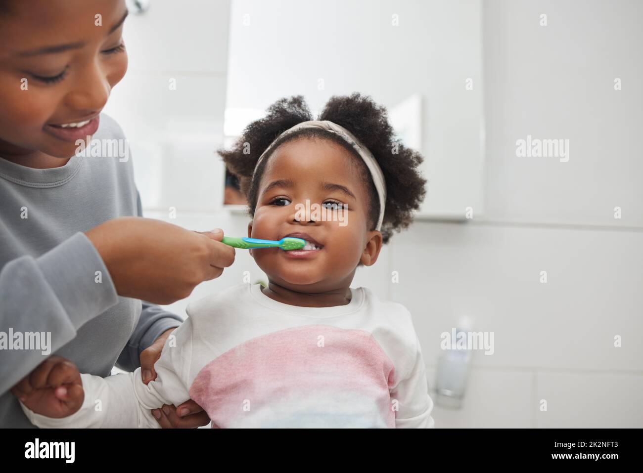 Mom will help her keep her baby teeth clean. Shot of a mother brushing