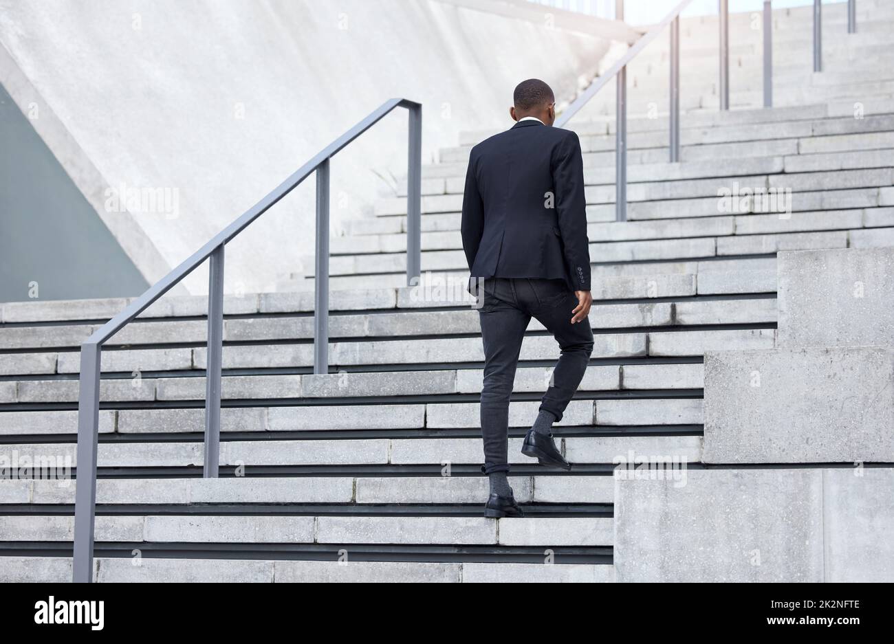 Walking up to success. Shot of an unrecognizable businessman walking up stairs in the city. Stock Photo