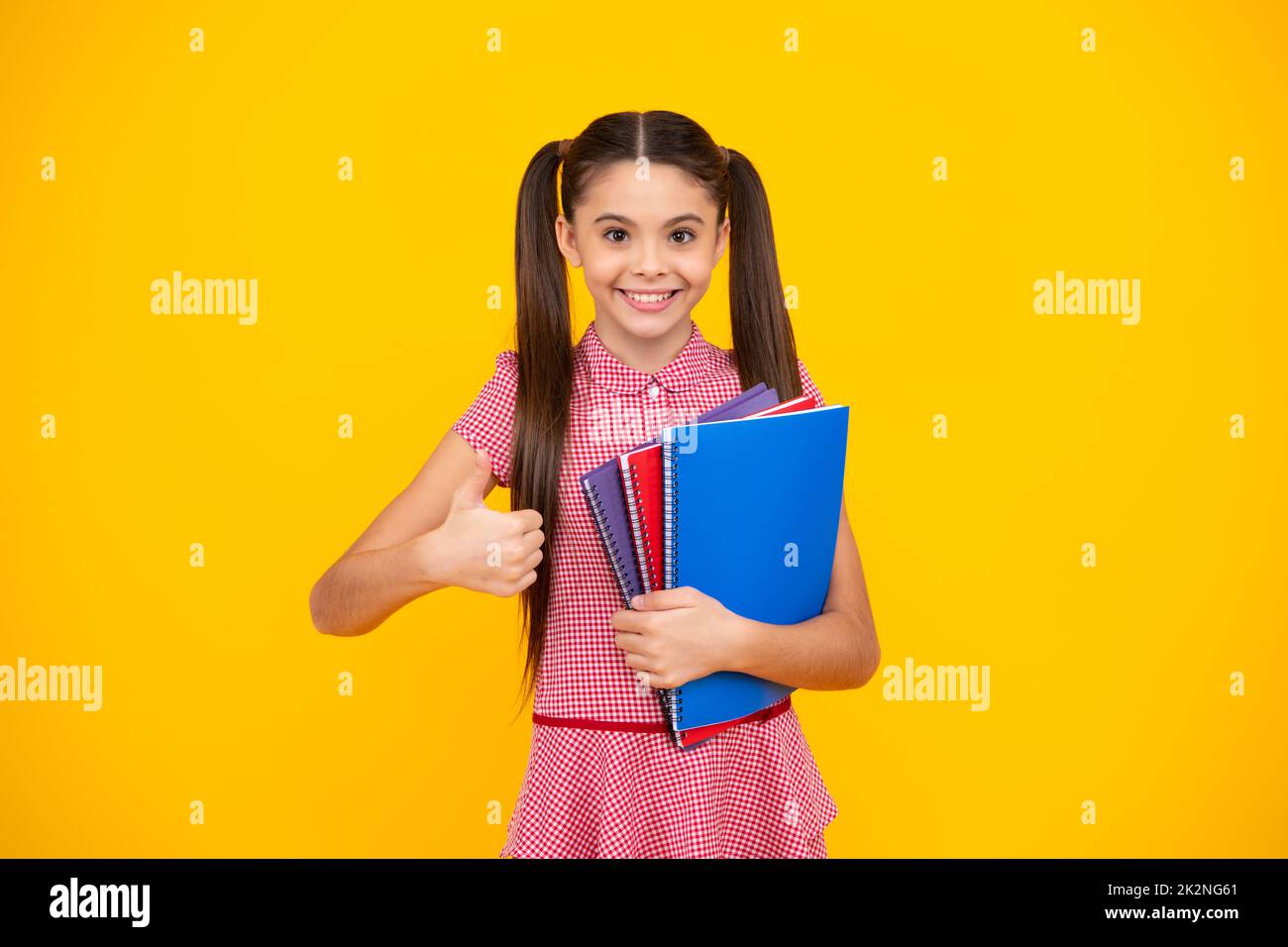 Teen girl pupil hold books, notebooks, isolated on yellow background, copy space. Back to school, teenage lifestyle, education and knowledge. Happy Stock Photo