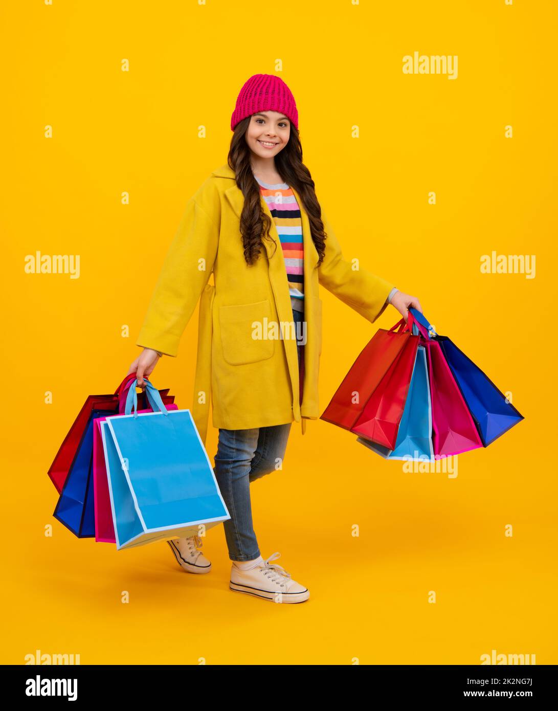 Stylish teen girl with shopping sale bags. Kid holding purchases. Fashion style of trendy child. Happy teenager, positive and smiling emotions of teen Stock Photo