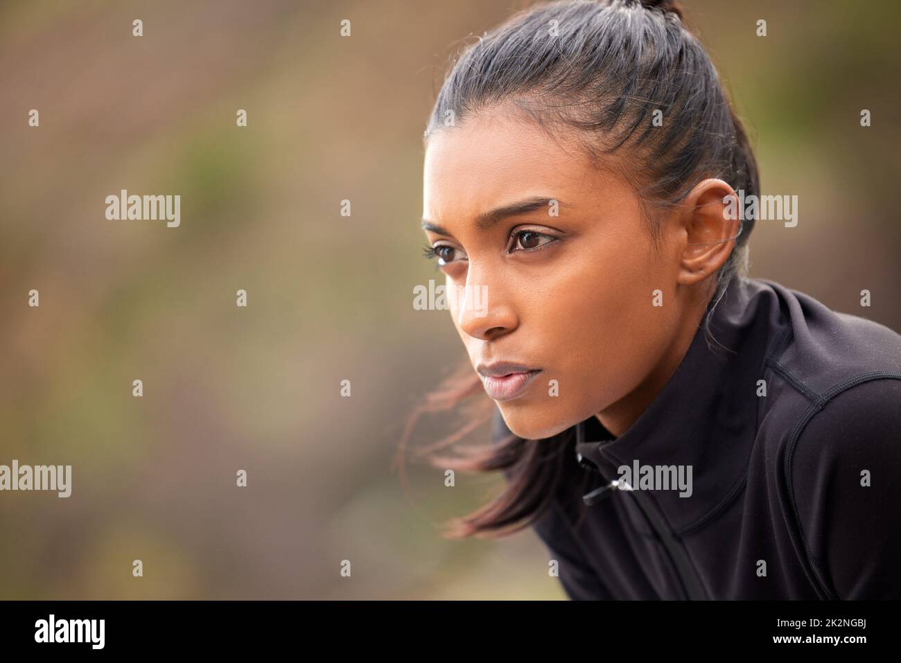 Just me and the road. Shot of a fit young woman catching her breathe while completing her jog outdoors. Stock Photo