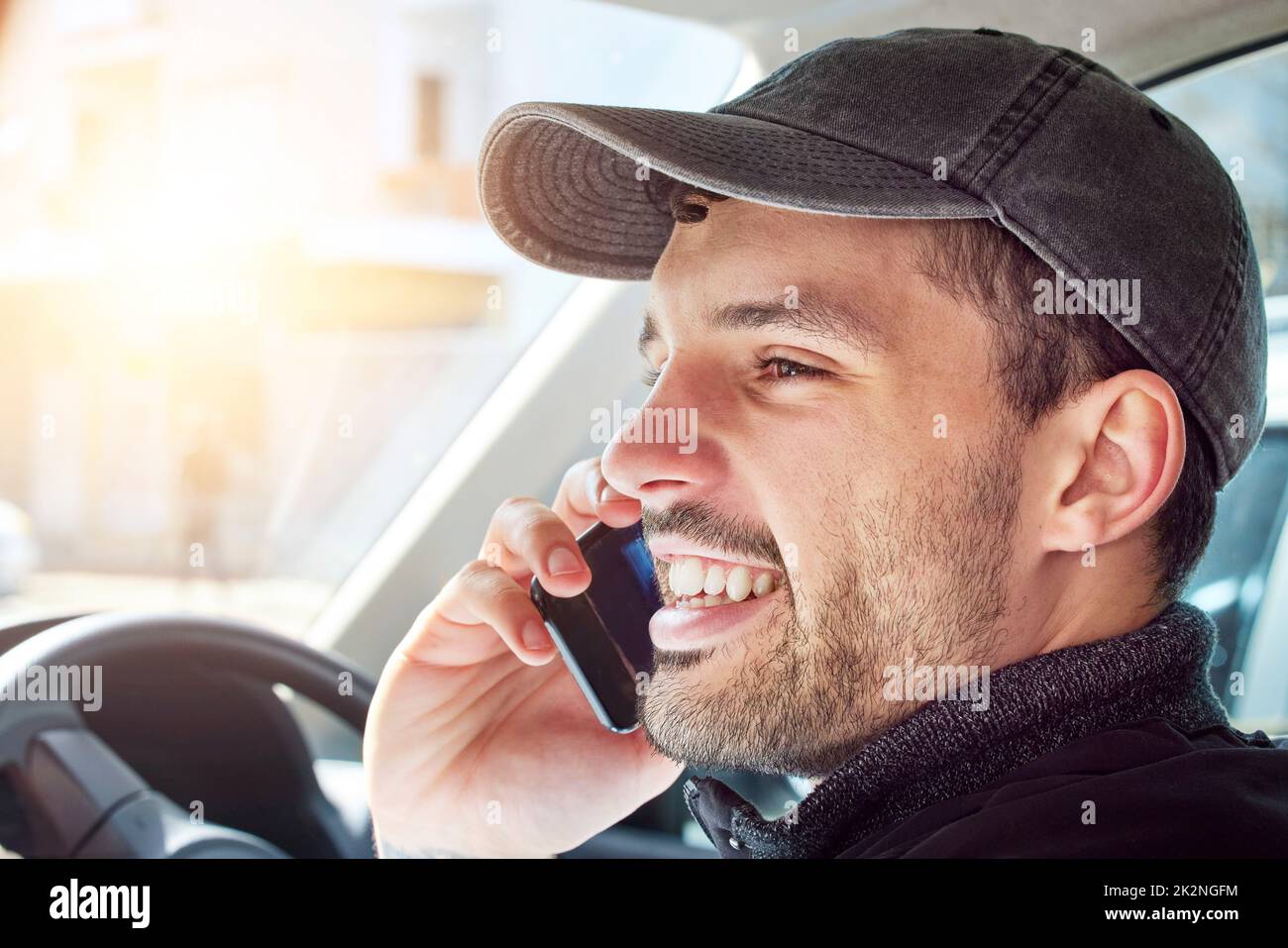 Calling a customer to make sure theyre home for a delivery. Shot of a young delivery man talking on a cellphone while sitting in a van. Stock Photo