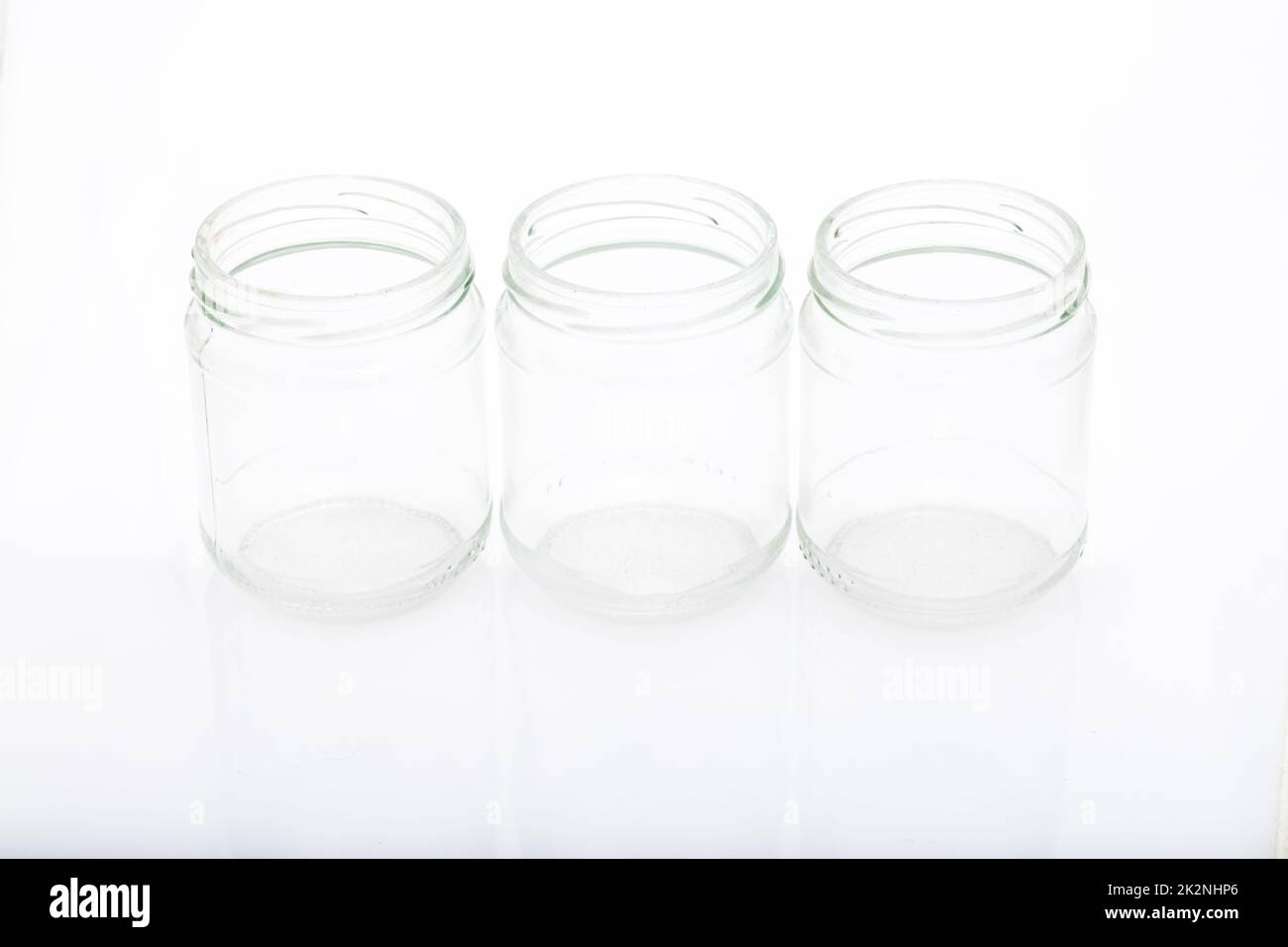 three little glass vases on a reflective surface Stock Photo Alamy
