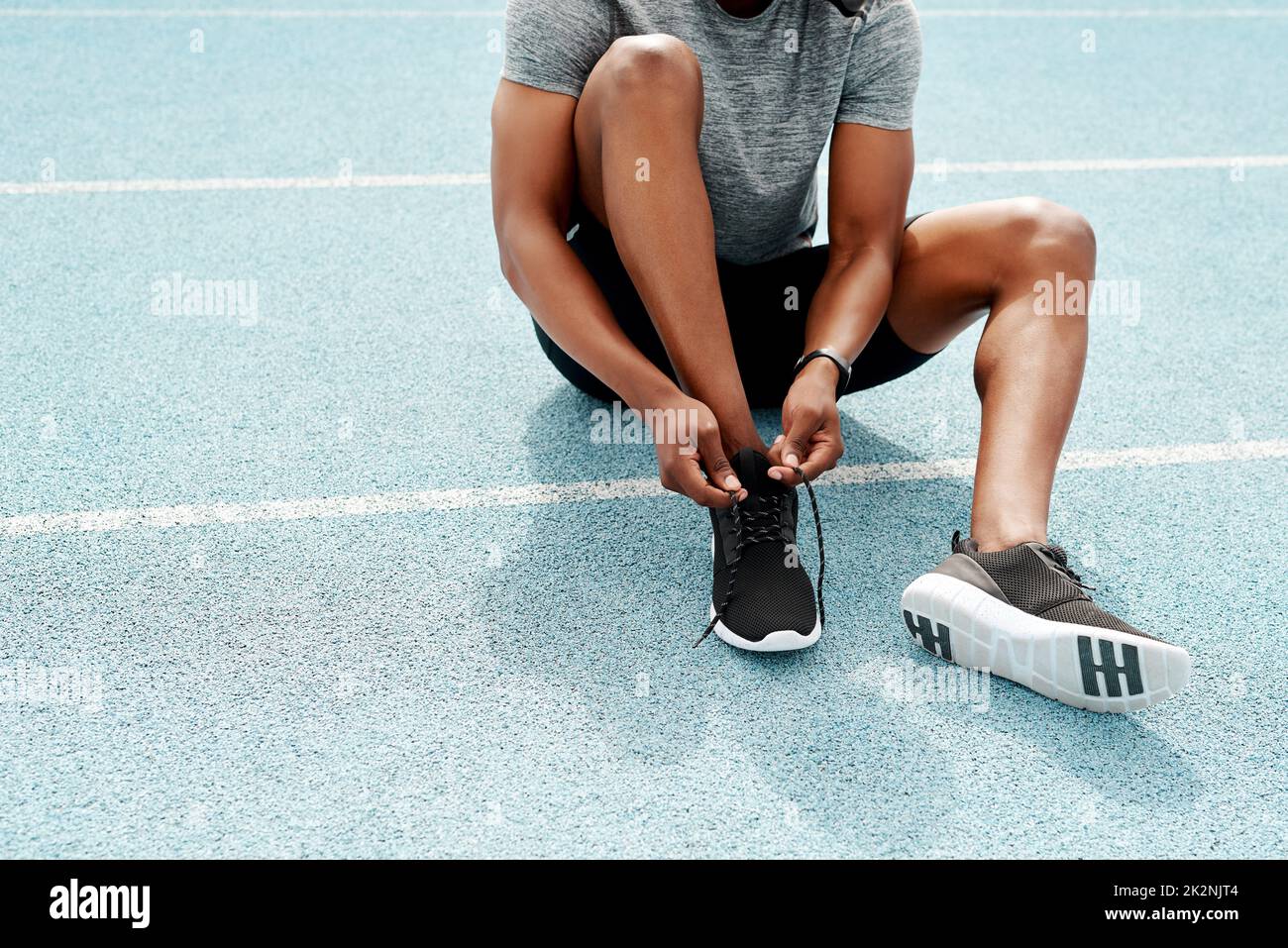 Making sure my laces are tied tight. Cropped shot of an unrecognizable athlete sitting and tying his shoelaces before going for a run alone. Stock Photo