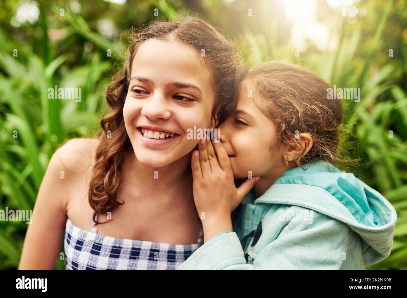 Ive got a secret to tell you. Cropped shot of an adorable little girl whispering into her sisters ear while out in the park. Stock Photo