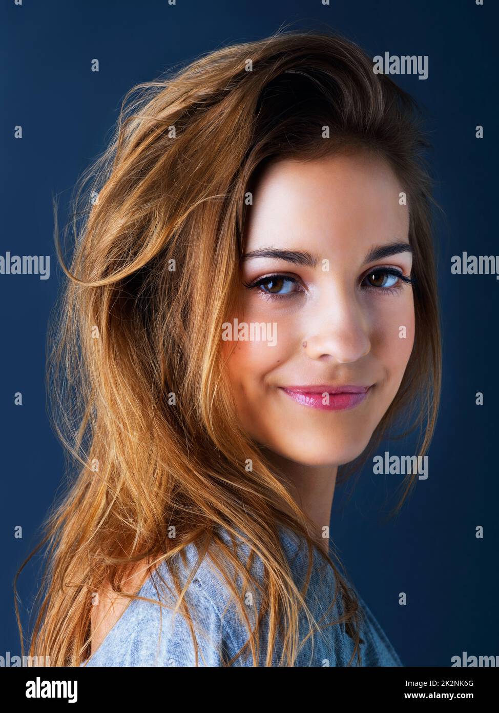 Shes got an easygoing spirit. Studio portrait of a cute teenage girl smiling and posing against a dark background. Stock Photo