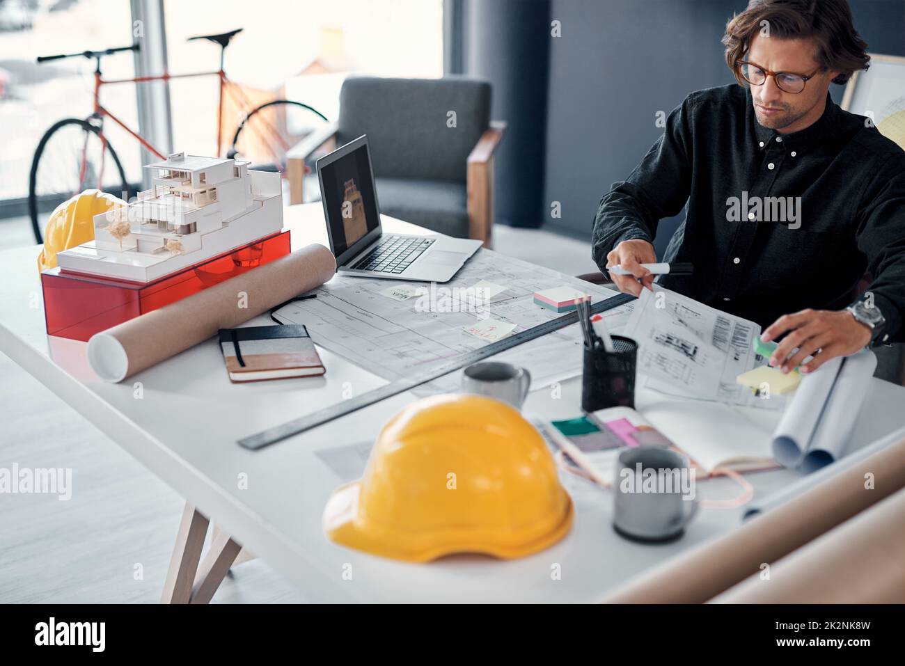 Proper planning saves you precious time, especially in this profession. Shot of a handsome young architect working on building plans and designs in his office. Stock Photo