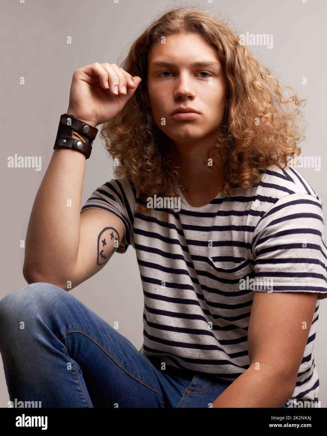 He is a trend setter. Portrait of a trendy young man sitting inside