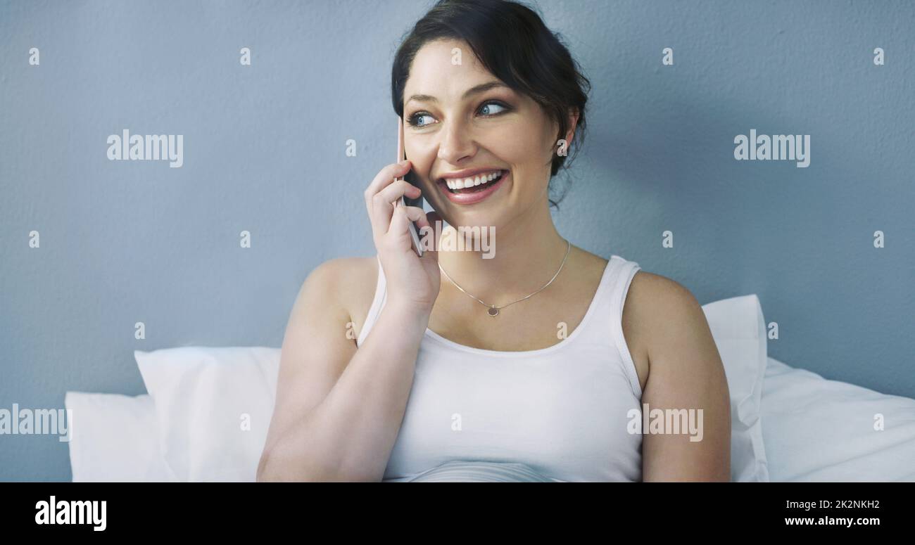 She woke up in a good mood today. Cropped shot of an attractive young woman talking on her cellphone while sitting in bed at home. Stock Photo