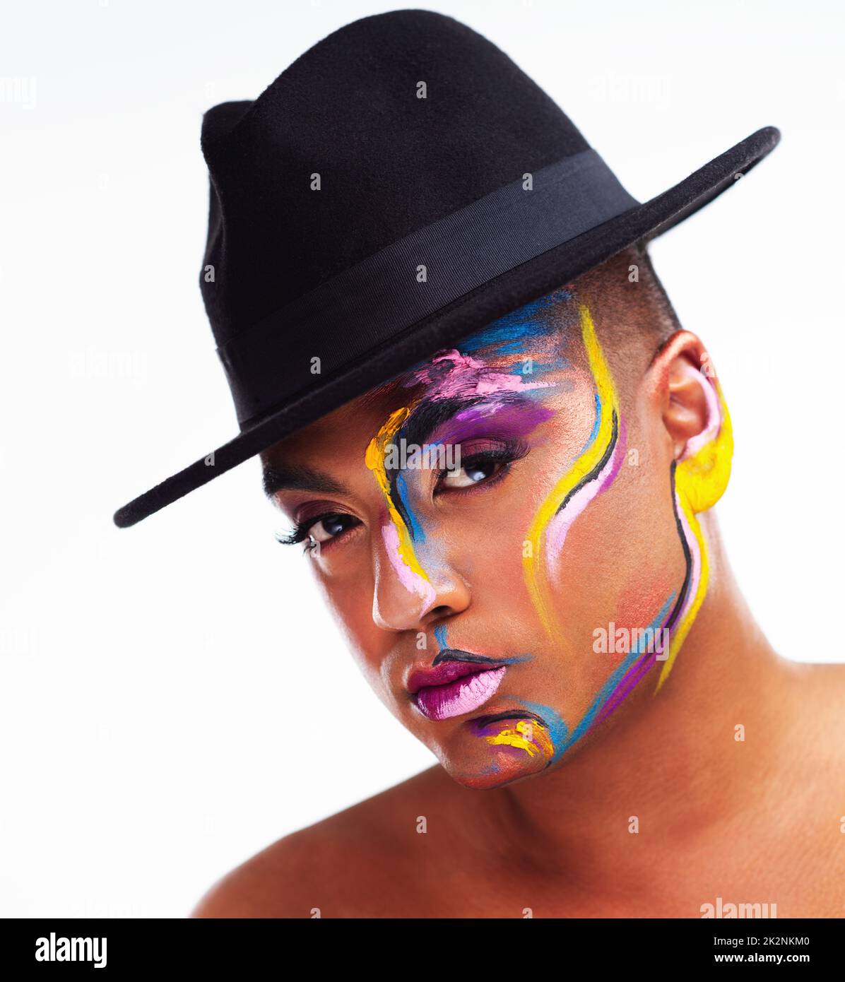 Be unapologetically you. Portrait of a gender fluid young man wearing face paint and a hat posing against a white background. Stock Photo