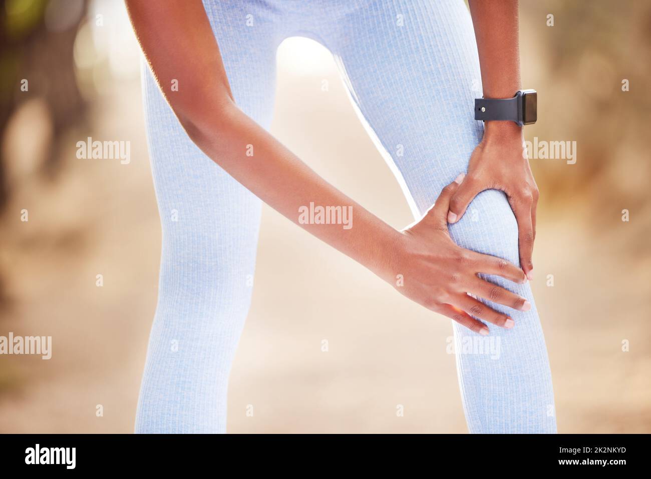 My knee has been acting up. Shot of a woman clutching her knee in pain during a jog. Stock Photo