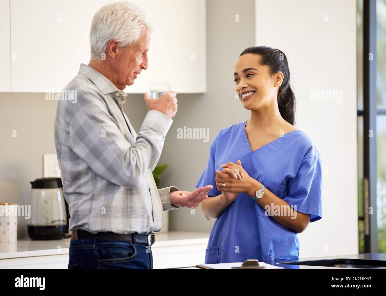 This medication should help your heart. Shot of a nurse watching her elderly patient taking his medication. Stock Photo