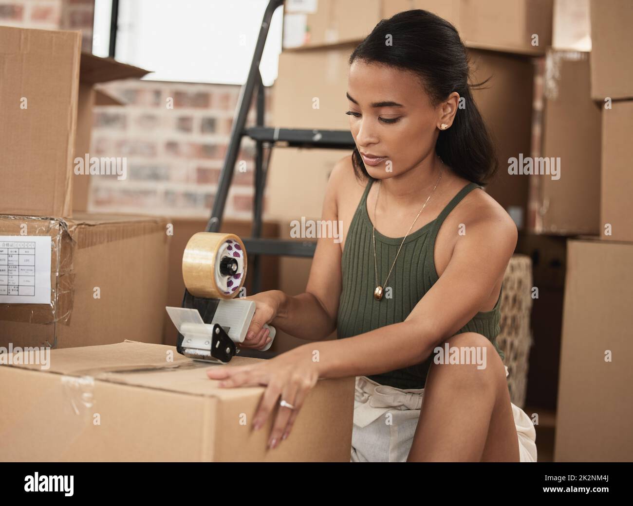 Everyone has their own reason for moving. Shot of a young woman packing up to move in a room at home. Stock Photo