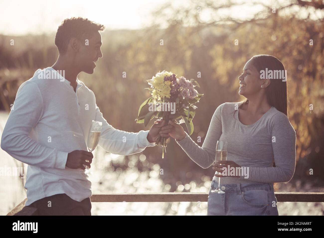 I had to pick flowers that matched your beauty. Shot of a handsome young man giving his girlfriend a bouquet of flowers while on a date outdoors. Stock Photo