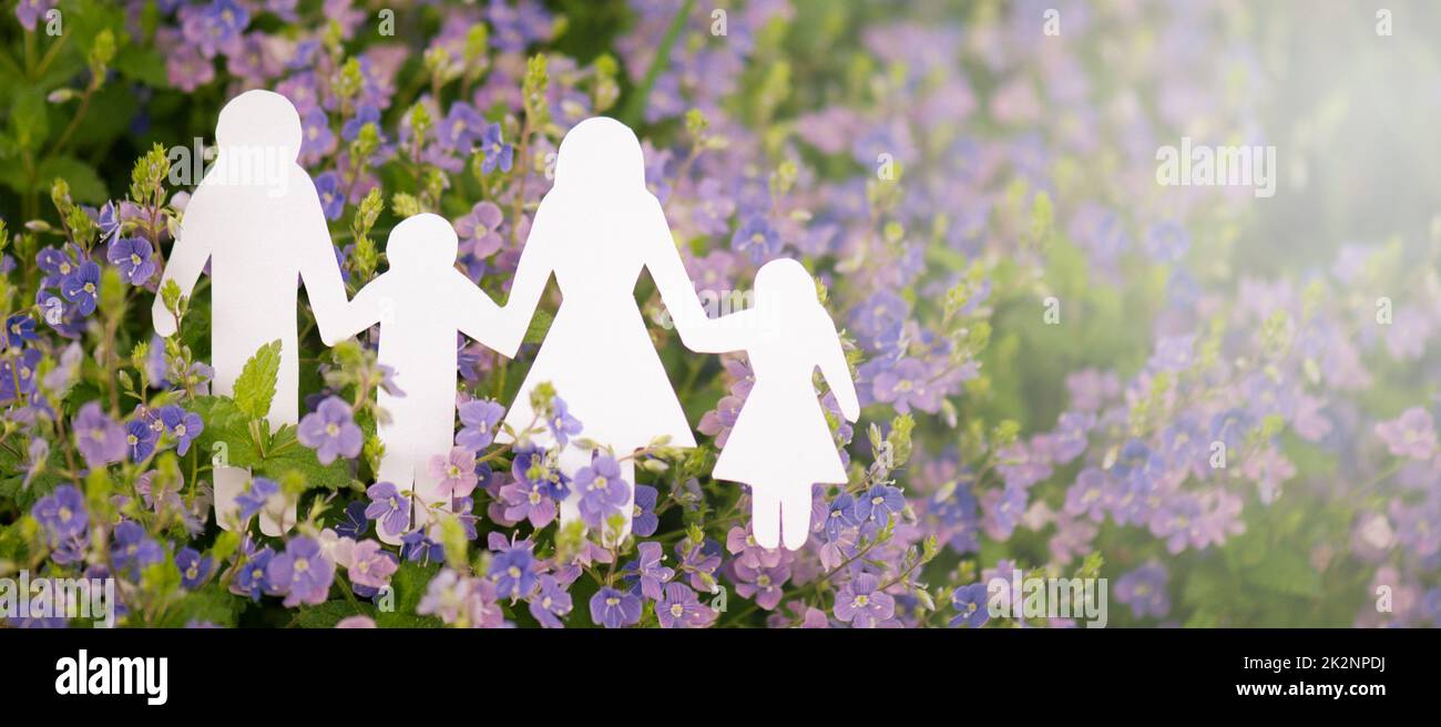 Family paper cut out is standing in a meadow, parents with daughter and son, environment concept, spring and summer season Stock Photo