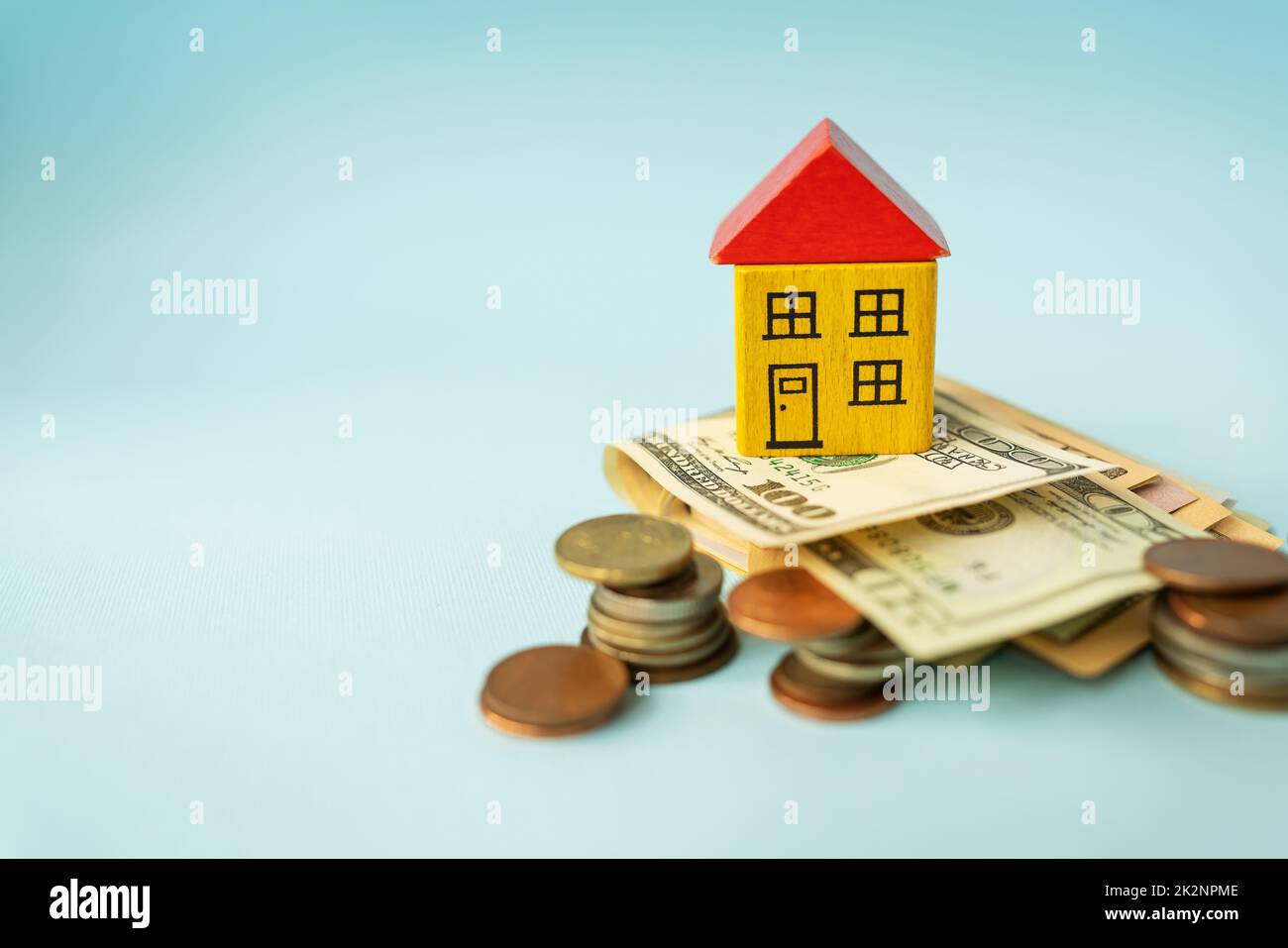 Money in international currency, including euro, dollar, a coin on which there is a toy house. The concept of mortgages, investments, loans, debts, housing purchases: apartments or houses. Stock Photo