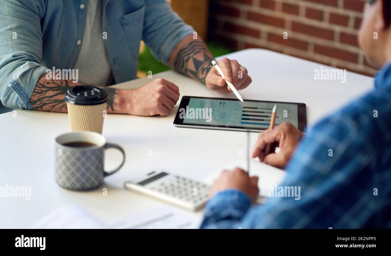 two businessmen using tablet computer discussing financial graph data on mobile touchscreen device in meeting Stock Photo