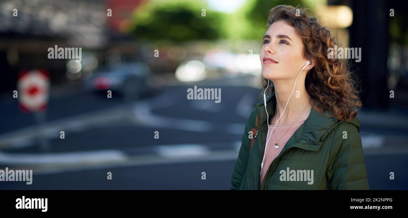 beautiful woman walking in city street listening to music wearing earphones urban lifestyle Stock Photo