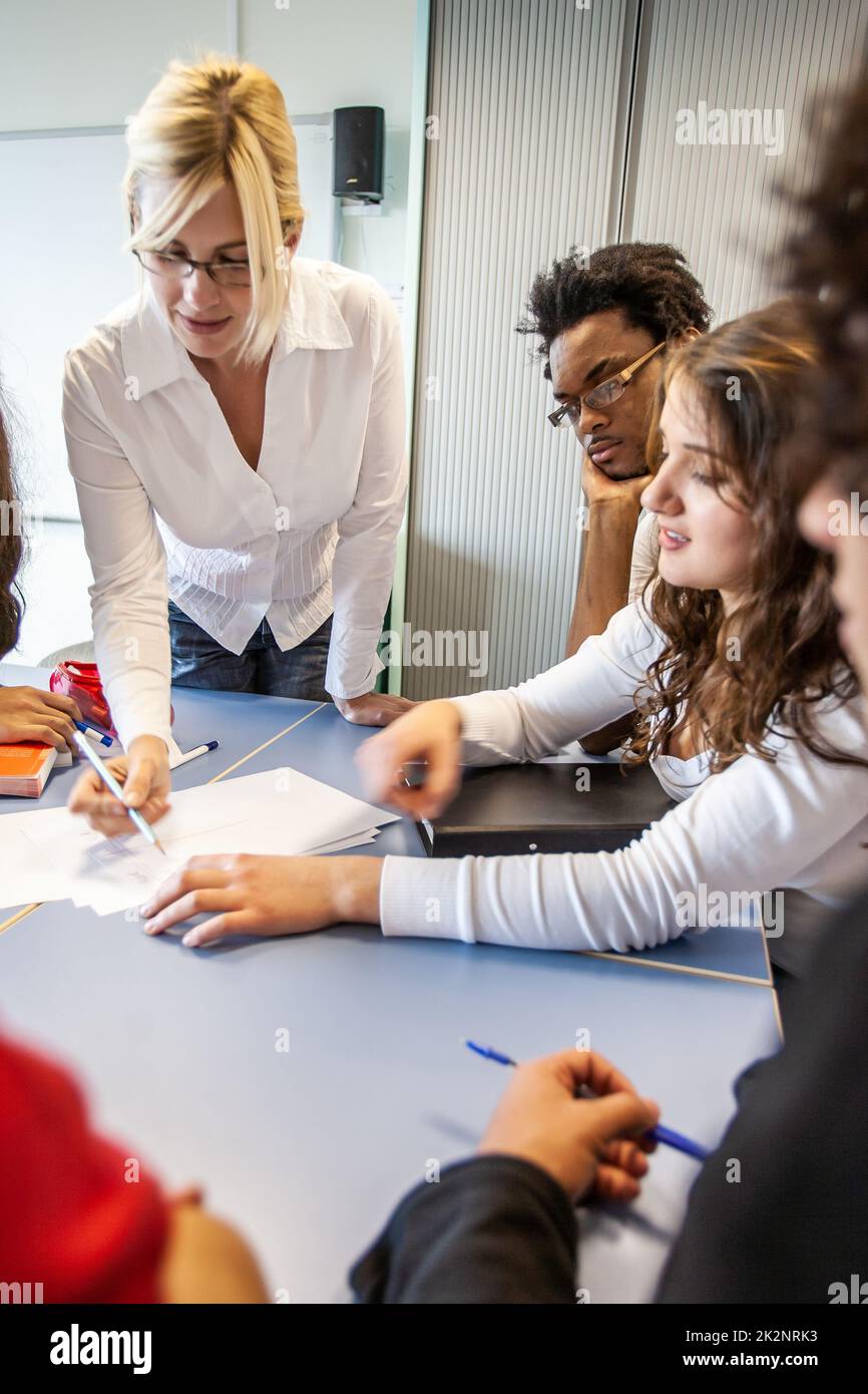 Teenage Students: Working with Teacher. A group of students concentrating on a class project with their teacher. From a series of related images. Stock Photo