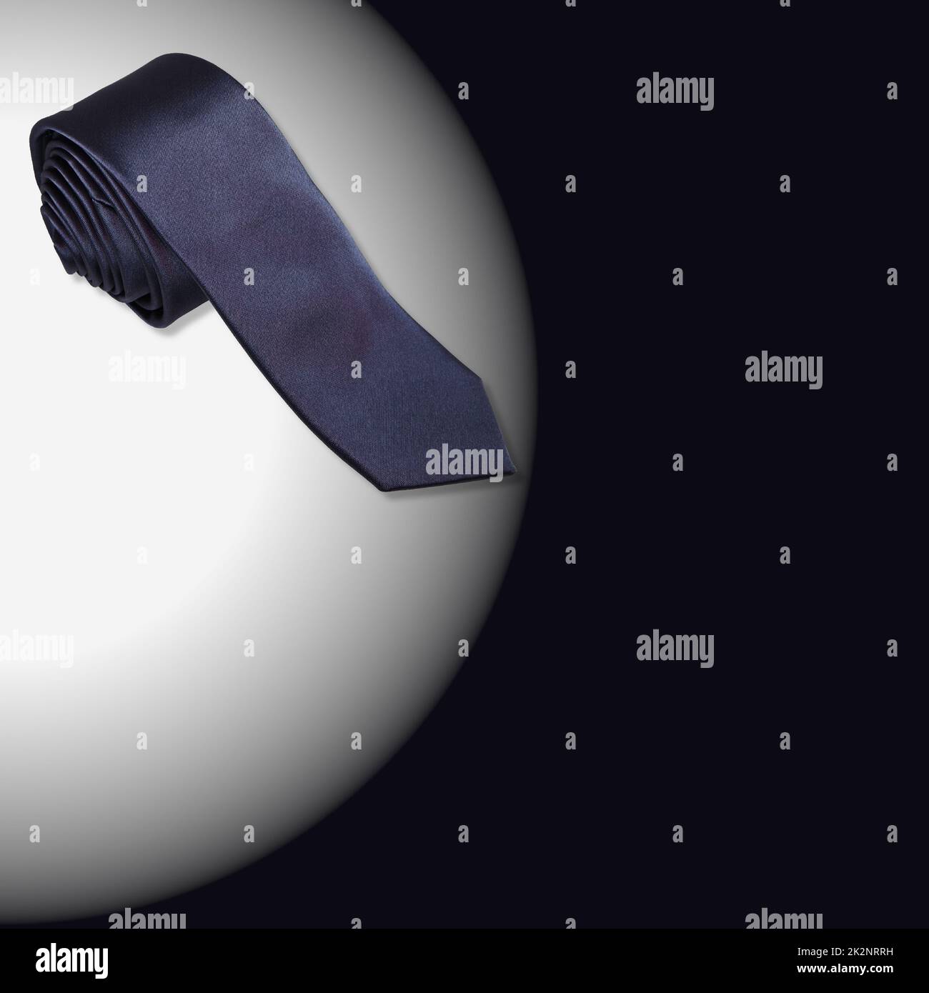 A navy blue rolled male necktie isolated on white and black background with copyspace Stock Photo