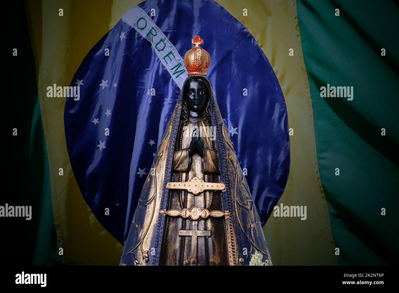 Statue of the image of Our Lady of Aparecida, mother of God in the Catholic religion, patroness of Brazil and Brazil flag Stock Photo