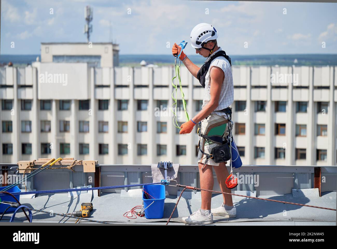 Industrial mountaineering workers washing glass windows of high-rise building, working with climbing ropes on the roof of skyscraper. Stock Photo