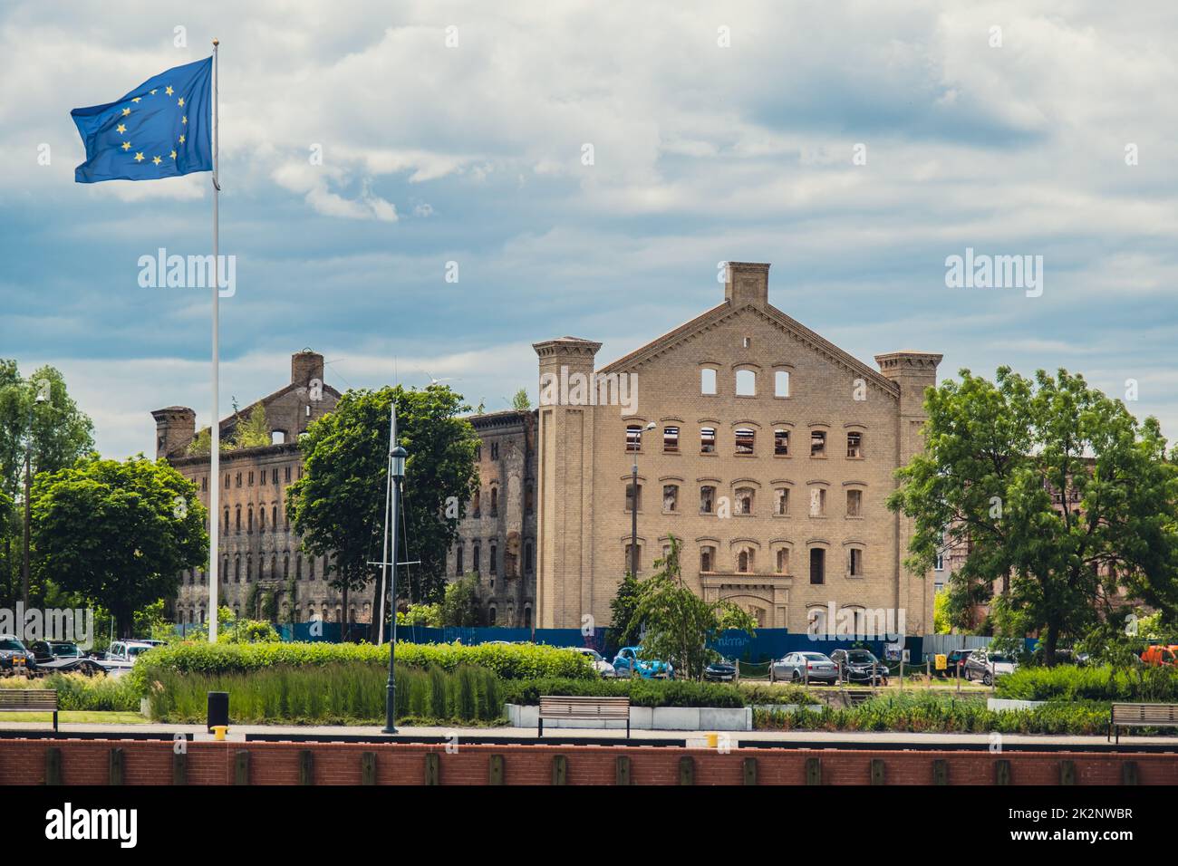 The EU Flag hanging on the pole, with an abandoned harbor building in the background Stock Photo